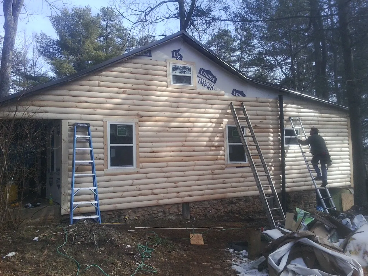 Ladders set against fresh log siding during an exterior remodel in Alderson