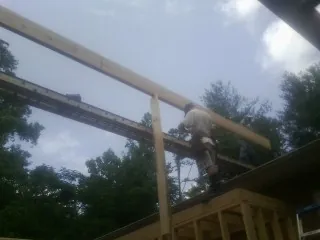 Carpenter setting a ridge beam over a new addition frame — Ice Dam Removal by Roofing Brothers in Alderson