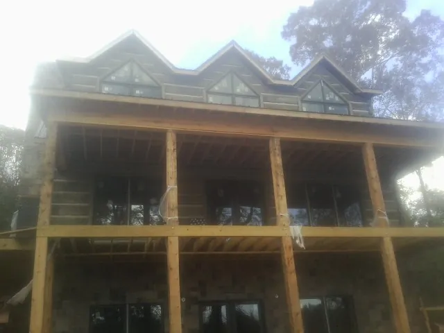 Dormers and porch framing on a large log home under construction — Roof Coating work by our crew in Alderson