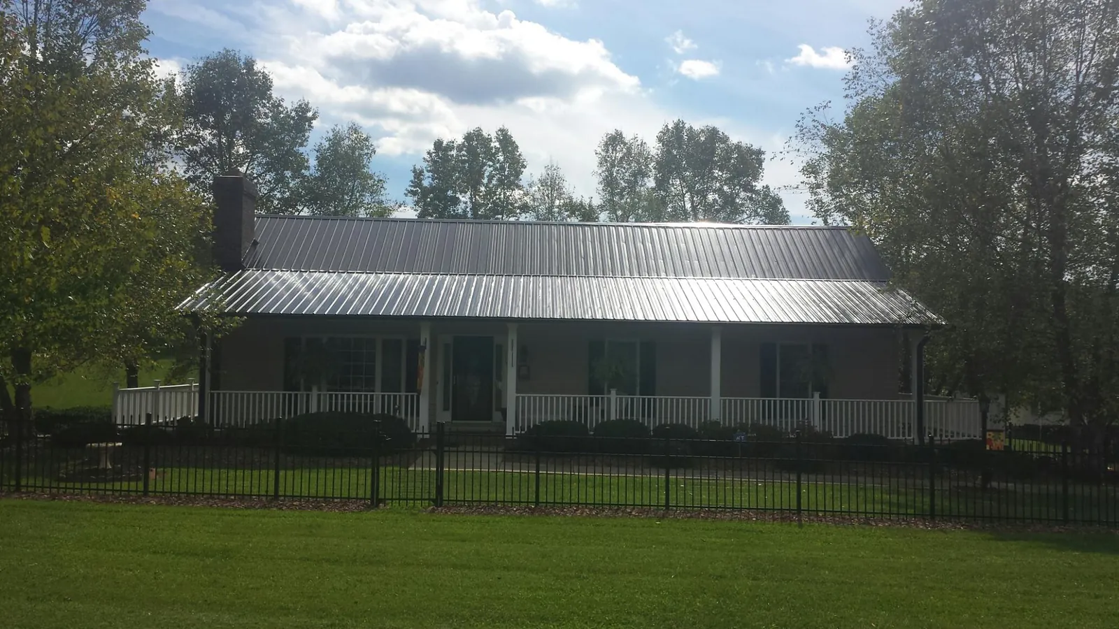 Gray metal roof on a brick ranch with a full width front porch — Gutter Guard Installation work by our crew in Alderson