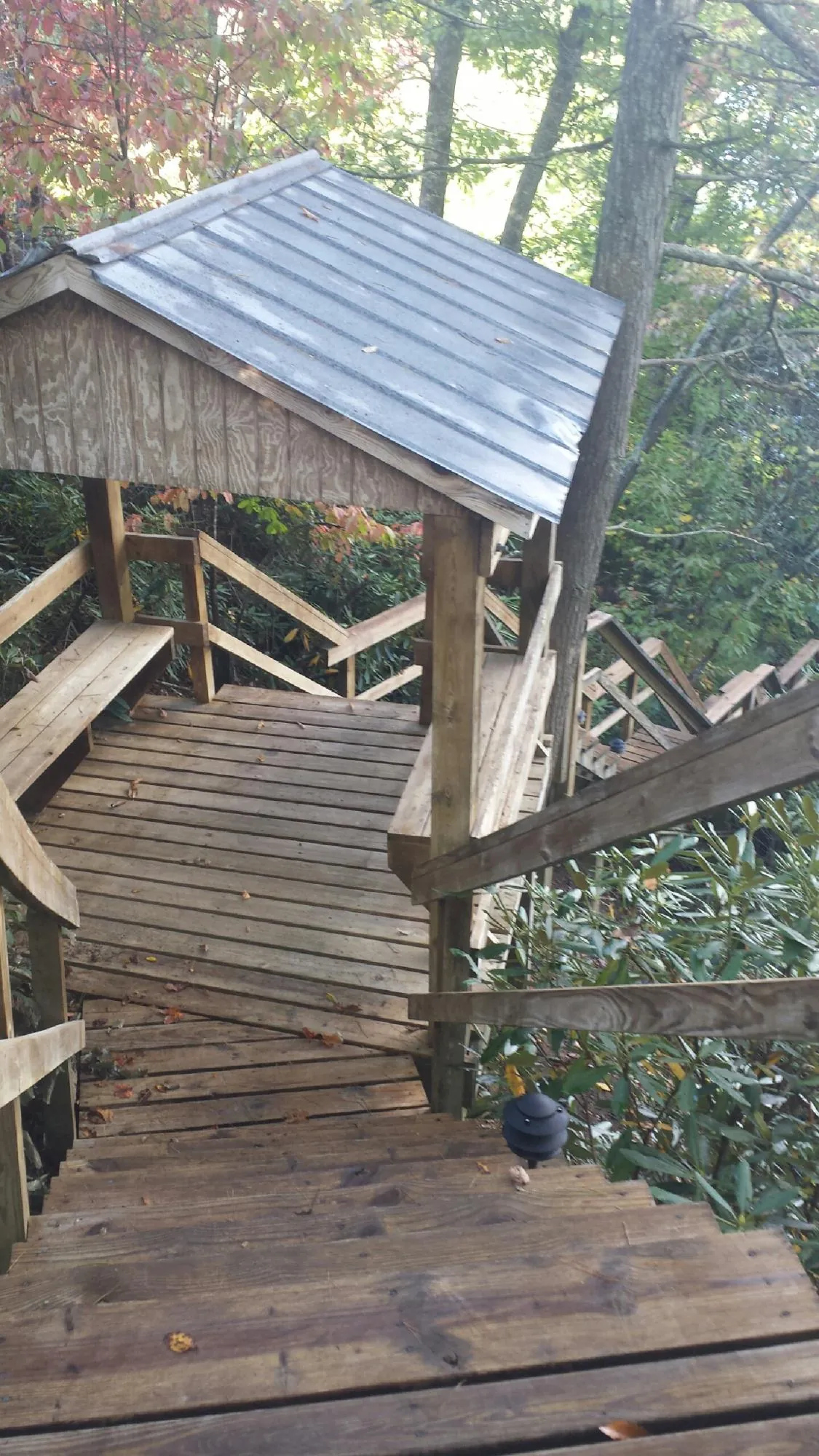 Metal roofed shelter over wooden steps on a wooded walkway — Skylight Repair & Installation work by our crew in Alderson
