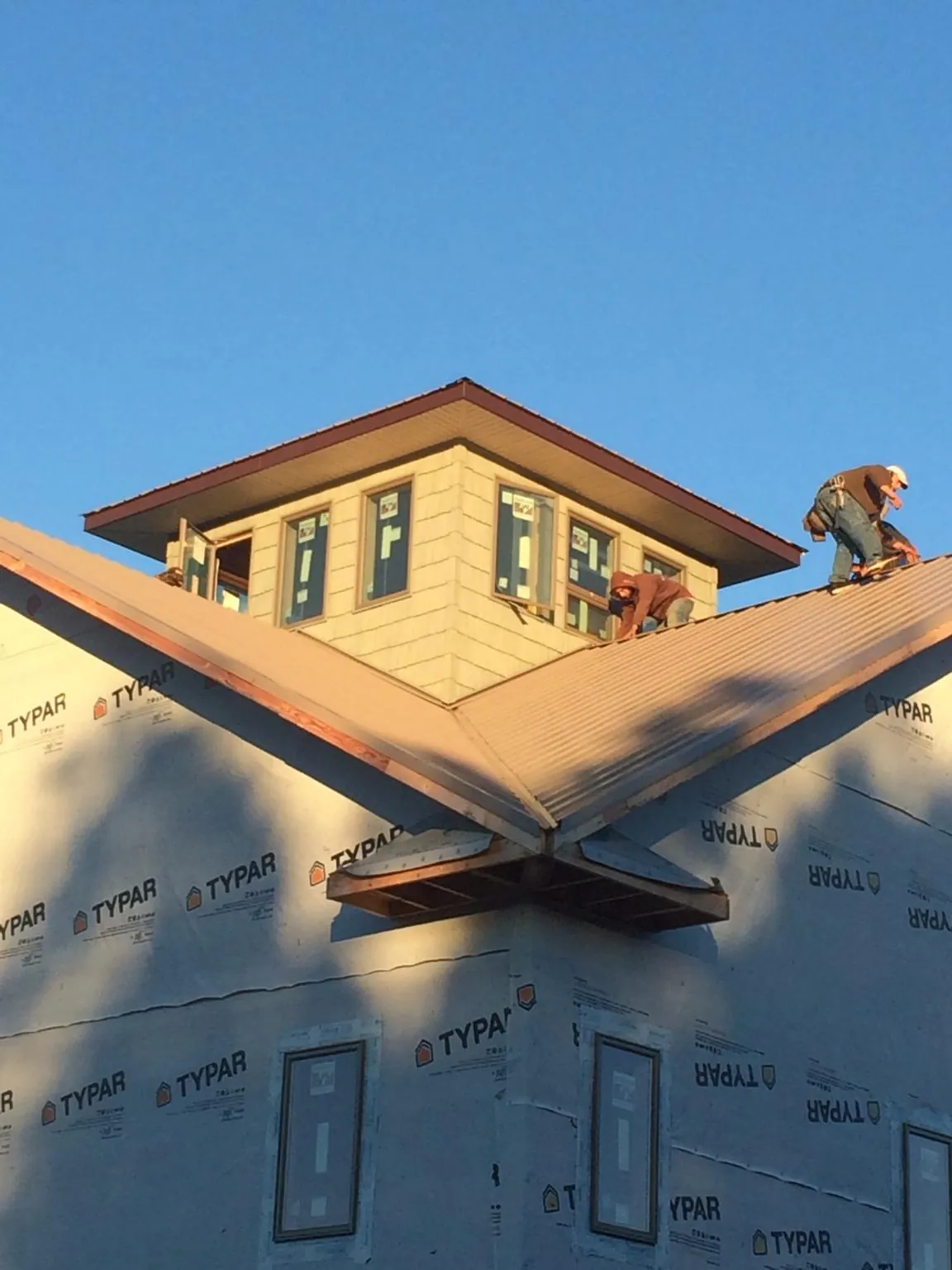 Roofers working around a rooftop cupola on a new metal roof at sunset — Roof Waterproofing in Alderson by Roofing Brothers